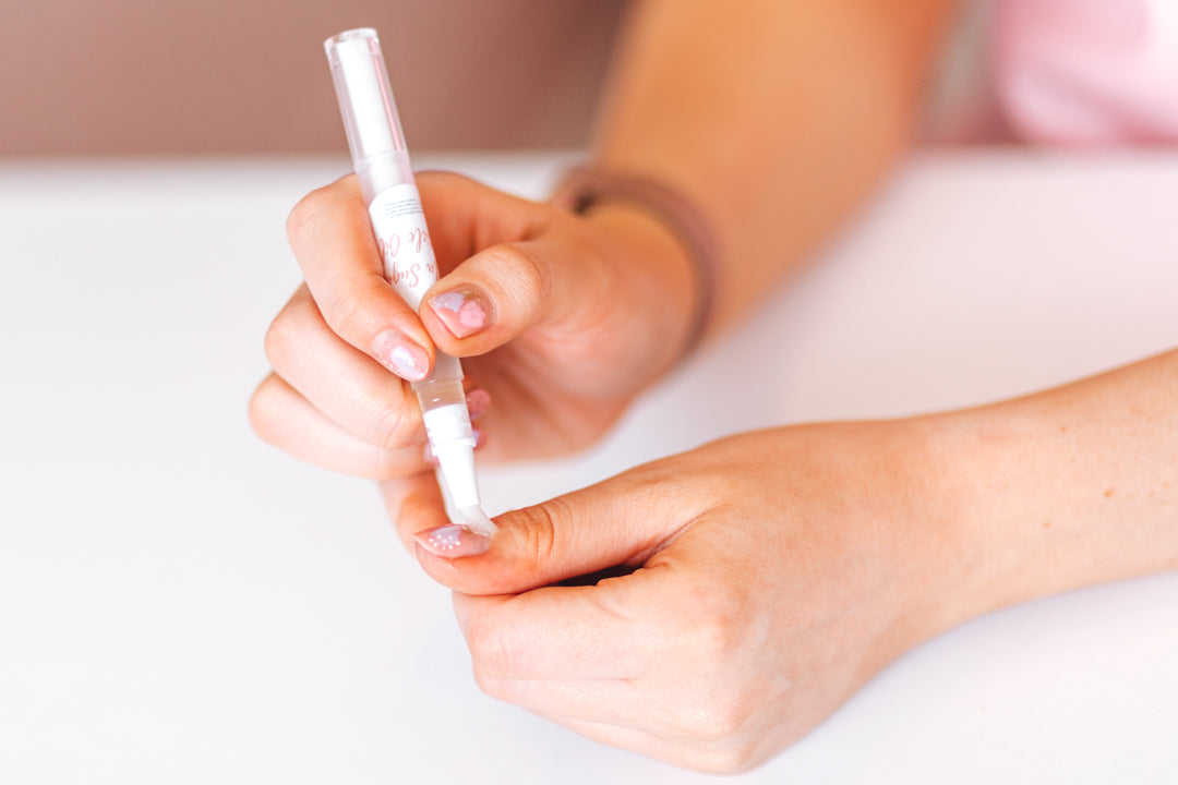 Lady applying cuticle oil to nails